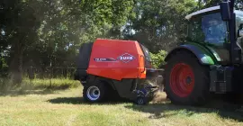 Mise en balles par KUHN FB 2130 dans un coin de champ avec des arbres en arrière-plan