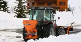 Distributeur VSA de sel, sable en action sur la route en montagne dans la neige