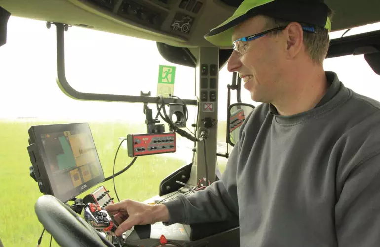 Agriculteur dans une cabine de tracteur qui pilote sa machine avec un terminal ISOBUS CCI 1200