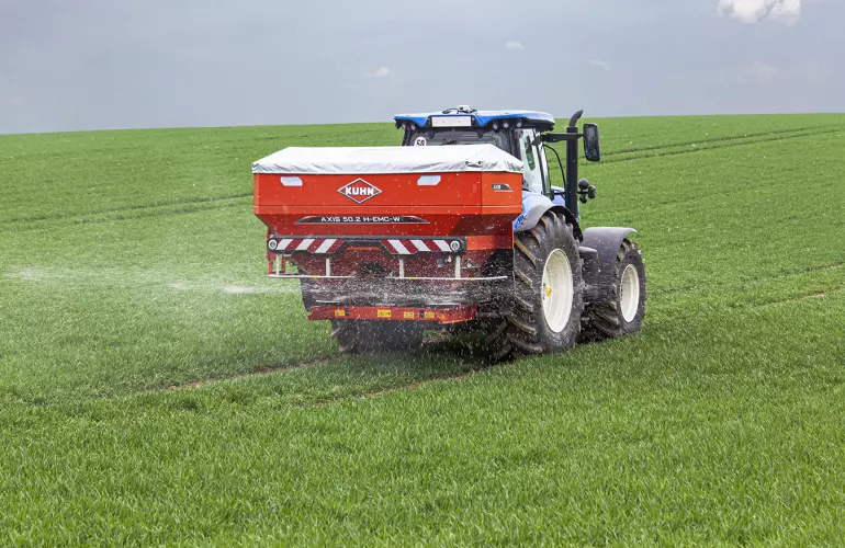 Vue sur l'épandeur à engrais porté AXIS 50.2 en pleine distribution.