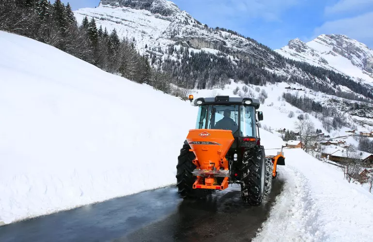Distributeur VSA de sel, sable en action sur la route en montagne dans la neige