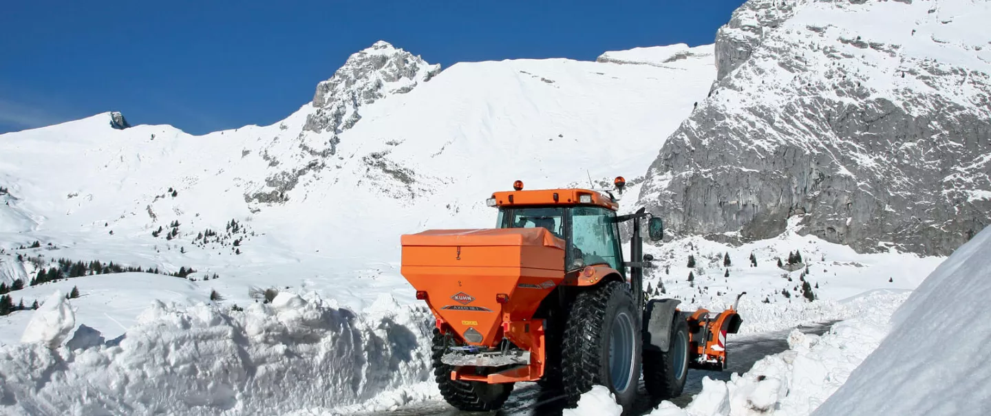 Distributeur AXEO de sel, sable, gravillons, engrais en action sur la route en montagne dans la neige