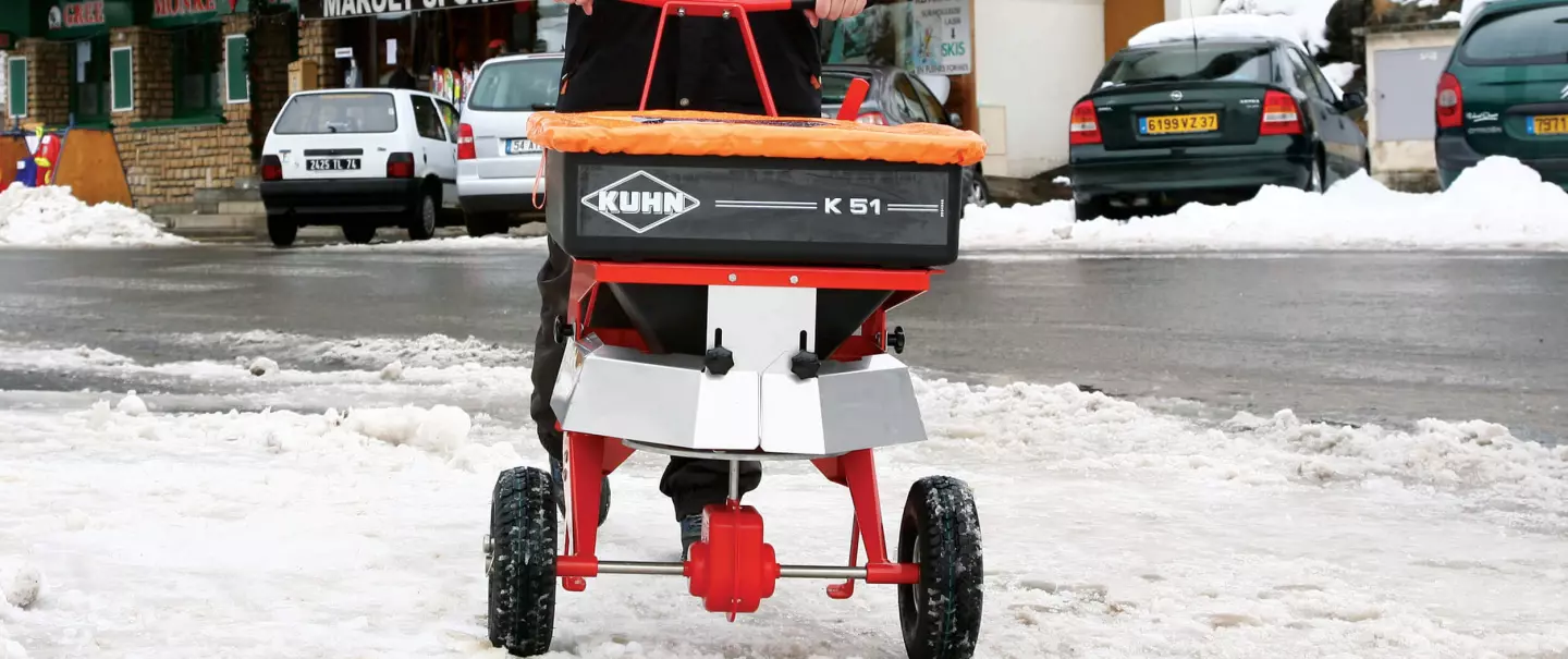 Distributeur poussé K51 de sel et sable en action en hiver dans la neige