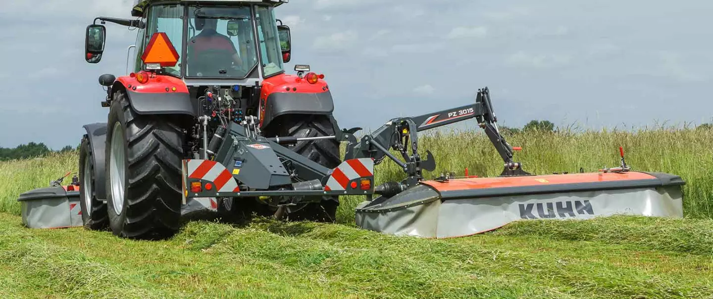 Faucheuse à tambour PZ 3015 avec tracteur Massey Ferguson travaillant dans un fourrage dense