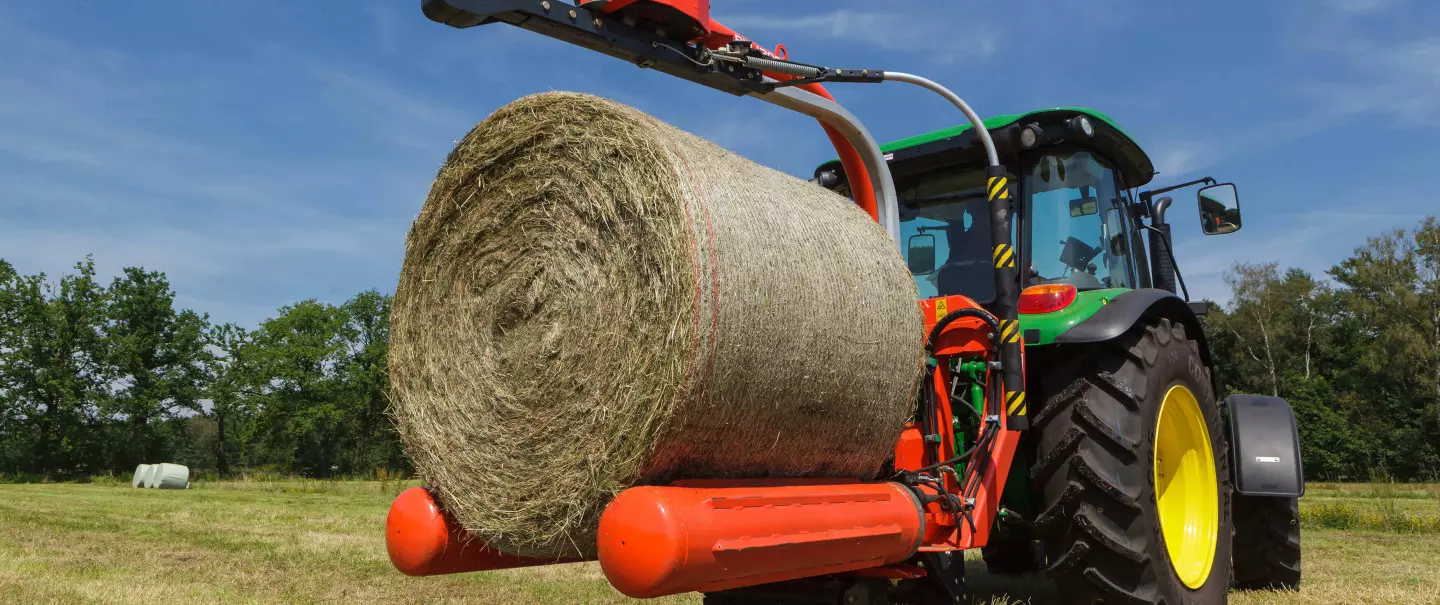 Une enrubanneuse RW 1200 portée 3 points attrape une balle pour l'enrubanner.