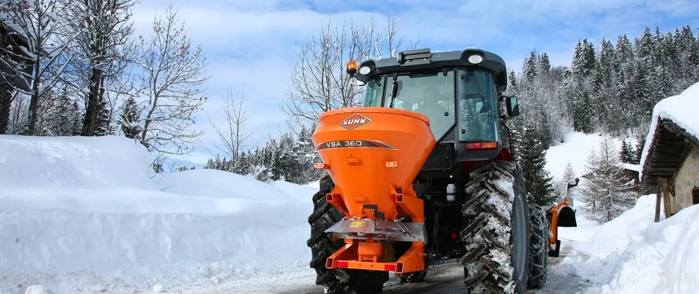 Distributeur VSA de sel, sable en action sur la route en montagne dans la neige
