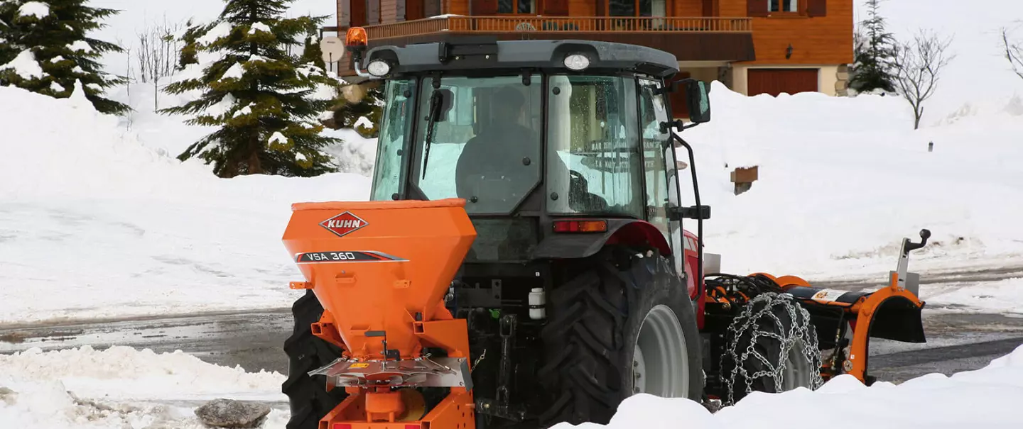 Distributeur VSA de sel, sable en action sur la route en montagne dans la neige